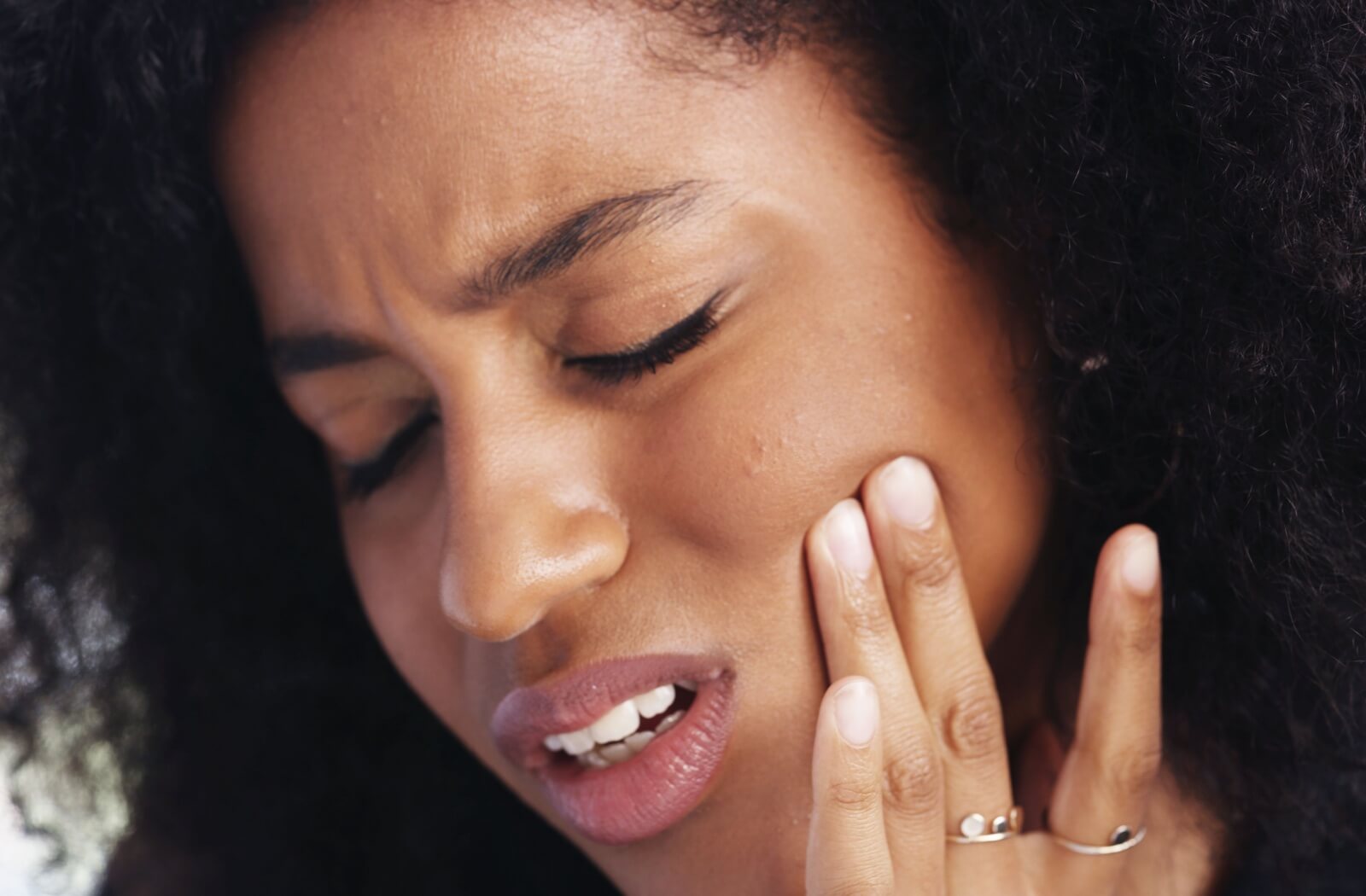A person touches their jaw in discomfort, showing symptoms of TMD.