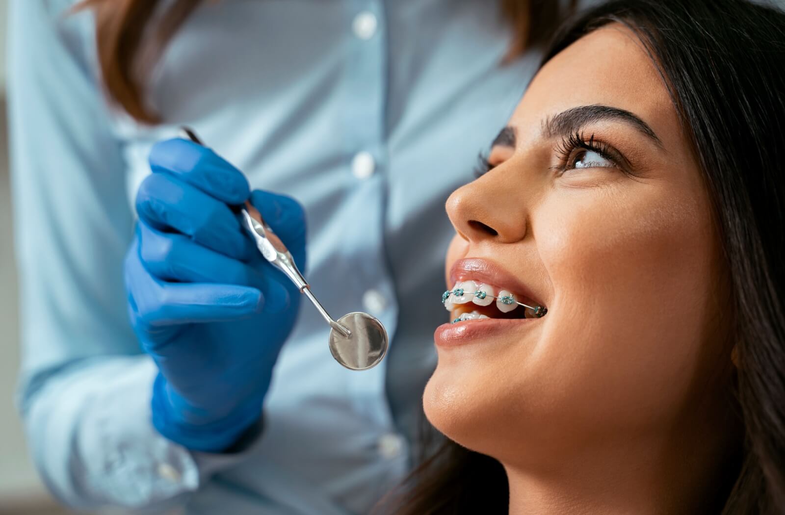 A person with braces smiles during a dental checkup.