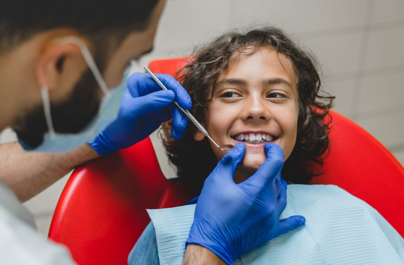 A dentist examining a smiling child's teeth during a check-up.